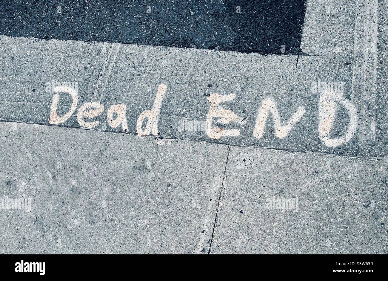 Handwritten sign in a sidewalk saying Dead End Stock Photo