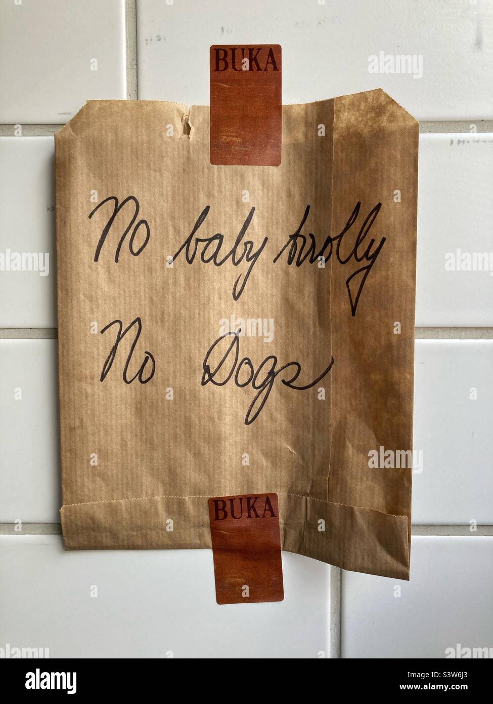 A sign Made out of a Paper Bag in the bakery Buka in Copenhagen saying: no baby trolley, no dogs. It was put up because of limited space in the store Stock Photo