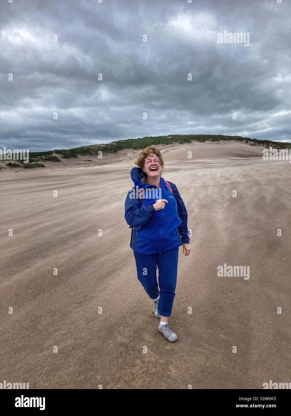 Woman laughing on Cheswick Sands Northumberland Stock Photo