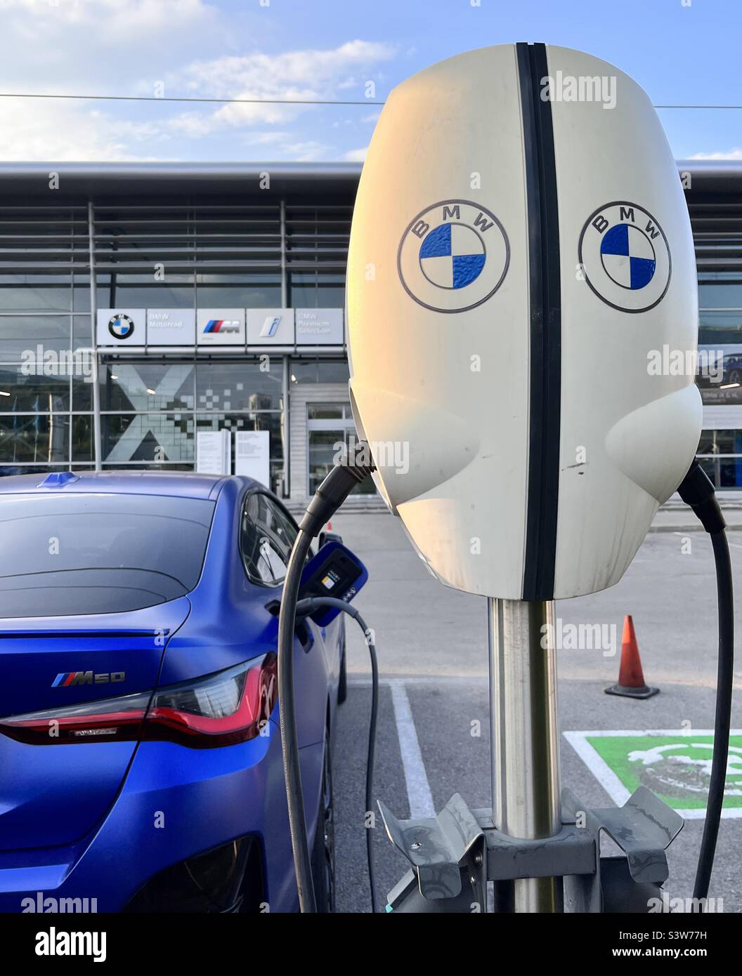 Blue BMW M50 electric car being charged at 22 kW Evbox charging station at the BMW and Mini main dealership in Sofia, Bulgaria Stock Photo