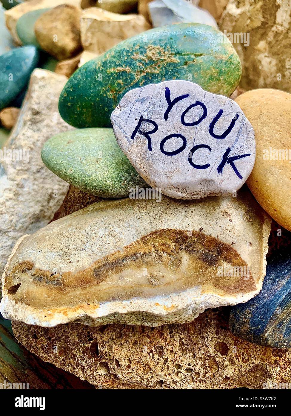Variety of natural rocks, on one someone has written, YOU ROCK, in black capital letters Stock Photo