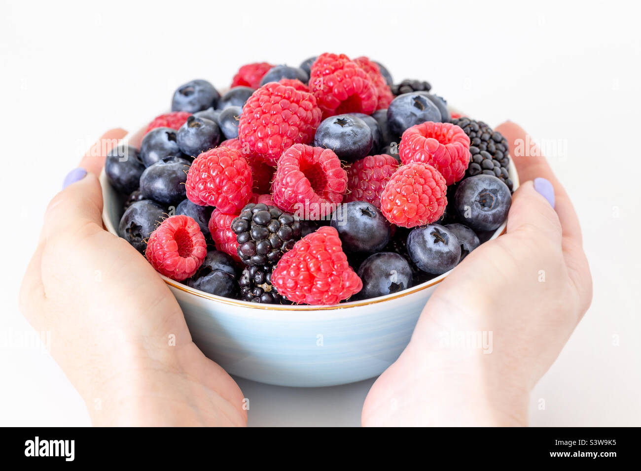 Bowl of fresh berries in hands, healthy breakfast option Stock Photo