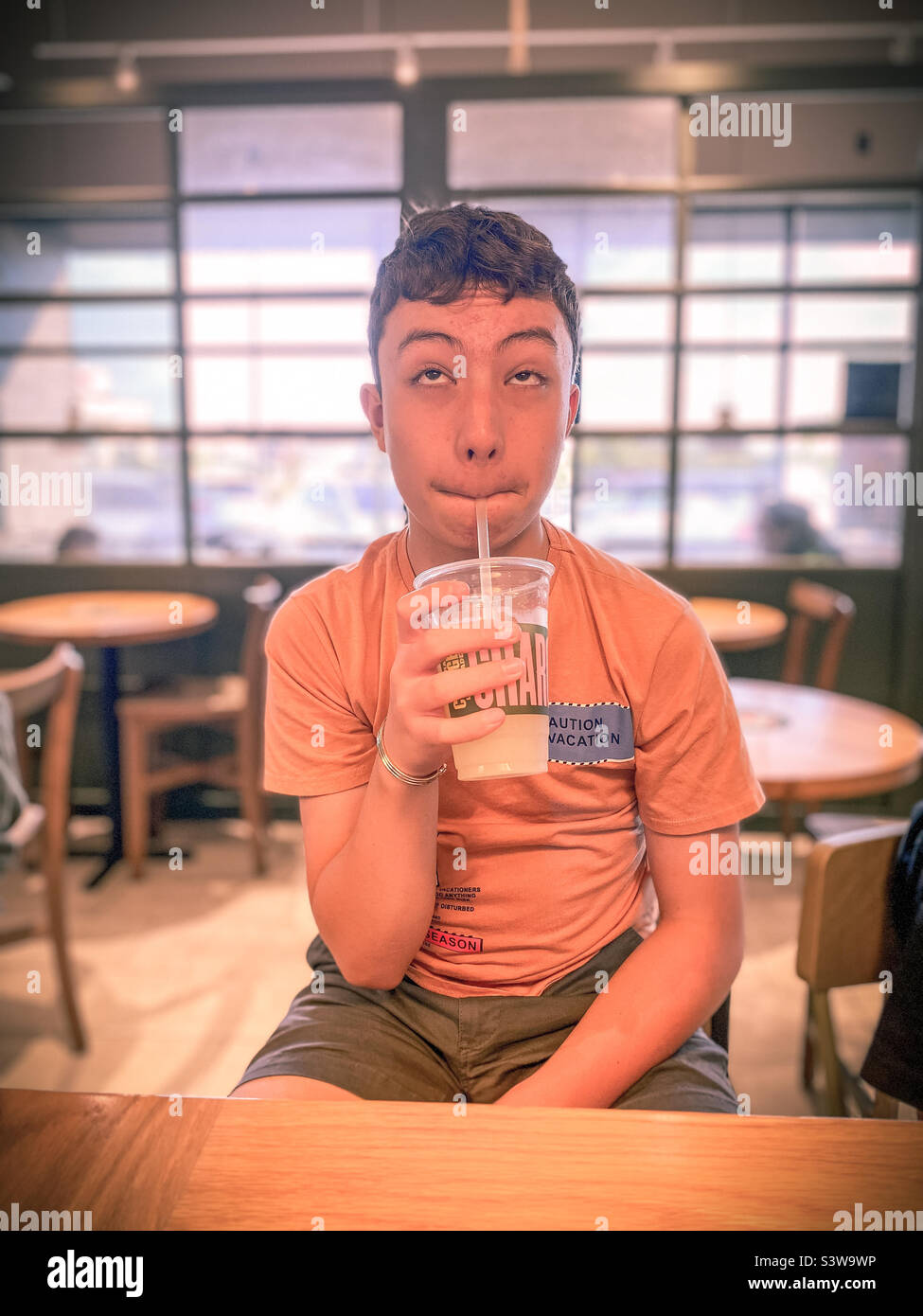 A teenager enjoying a cold drink - Smartphone Captured Stock Image