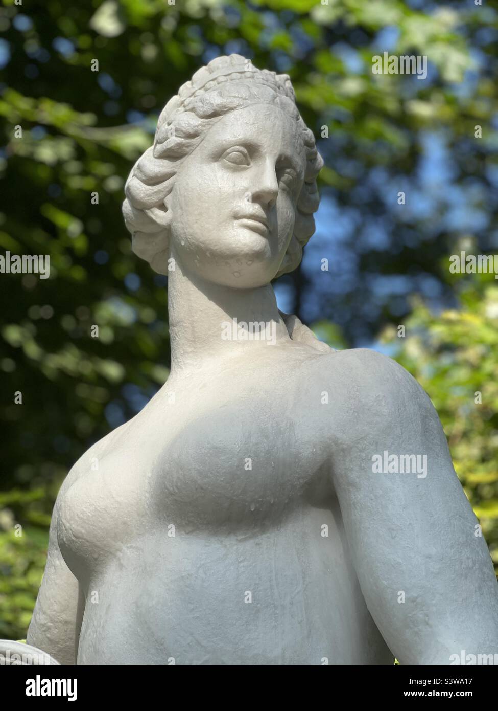 Antique white marble statue with dew drops on a green background. Art