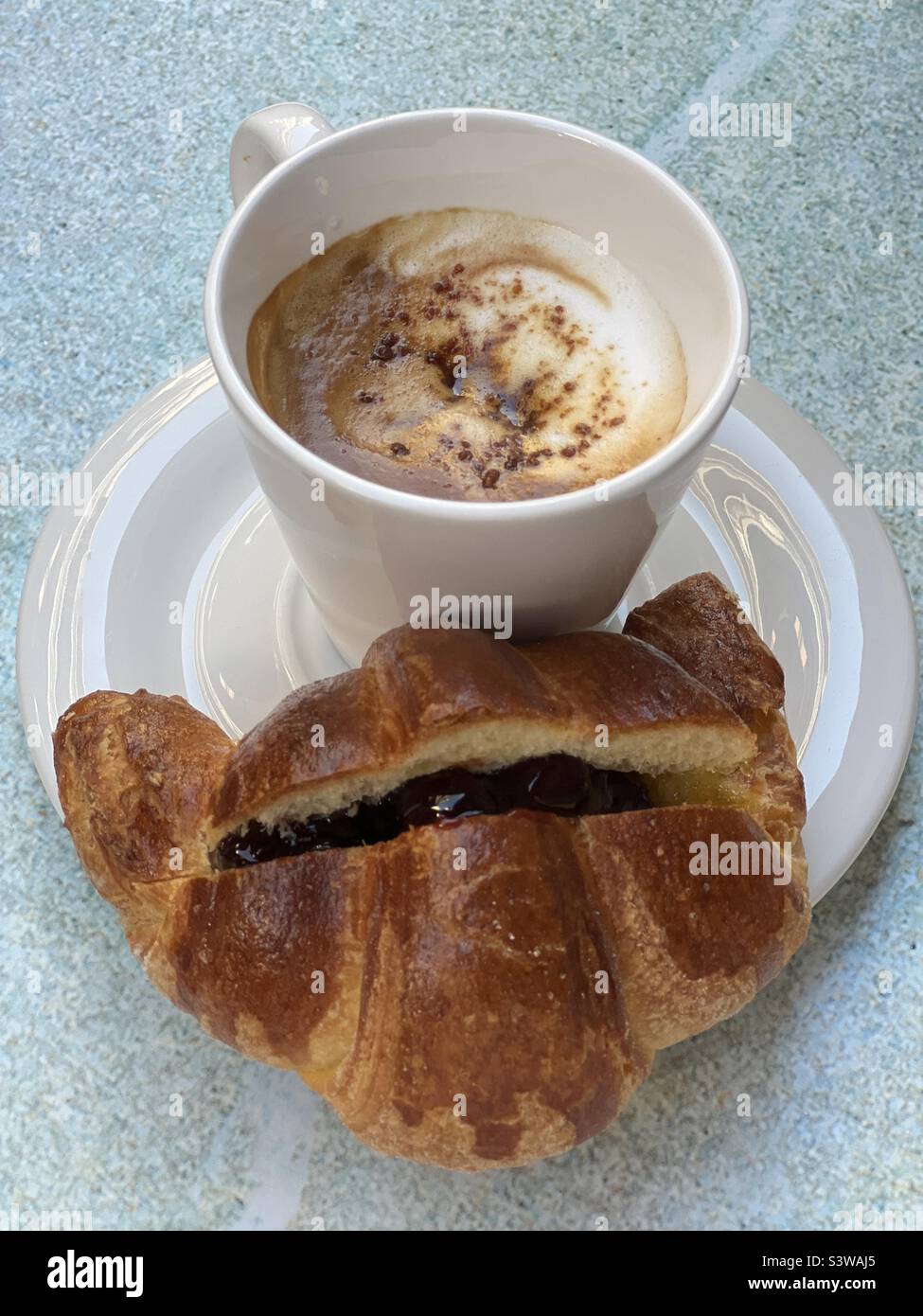 Breakfast with cappuccino and croissant with wild cherries Stock Photo