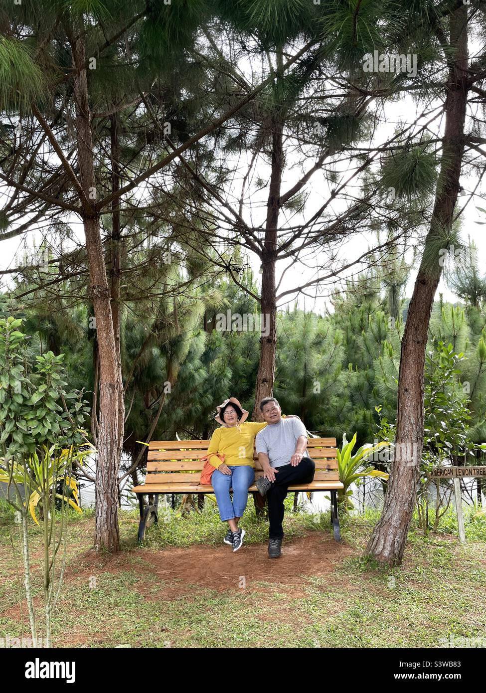 Asian Senior Couple Enjoying Retirement Relaxing On The Bench While