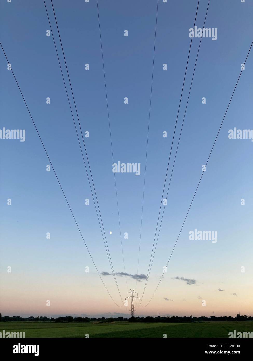 High-tension Power lines over a meadow und northern Germany at Dawn - Smartphone Captured Stock Image