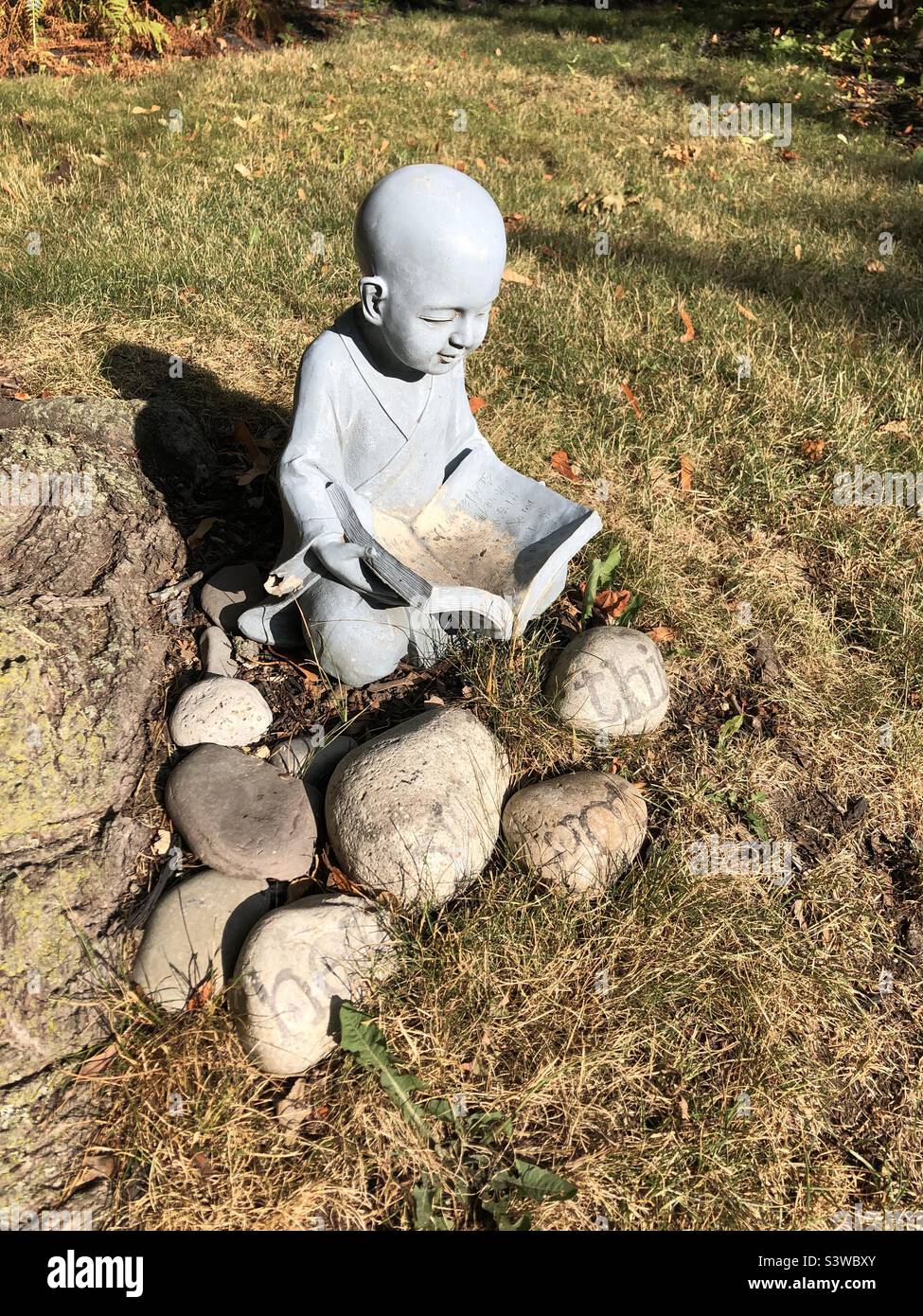 A garden Buddha statue reading Stock Photo Alamy