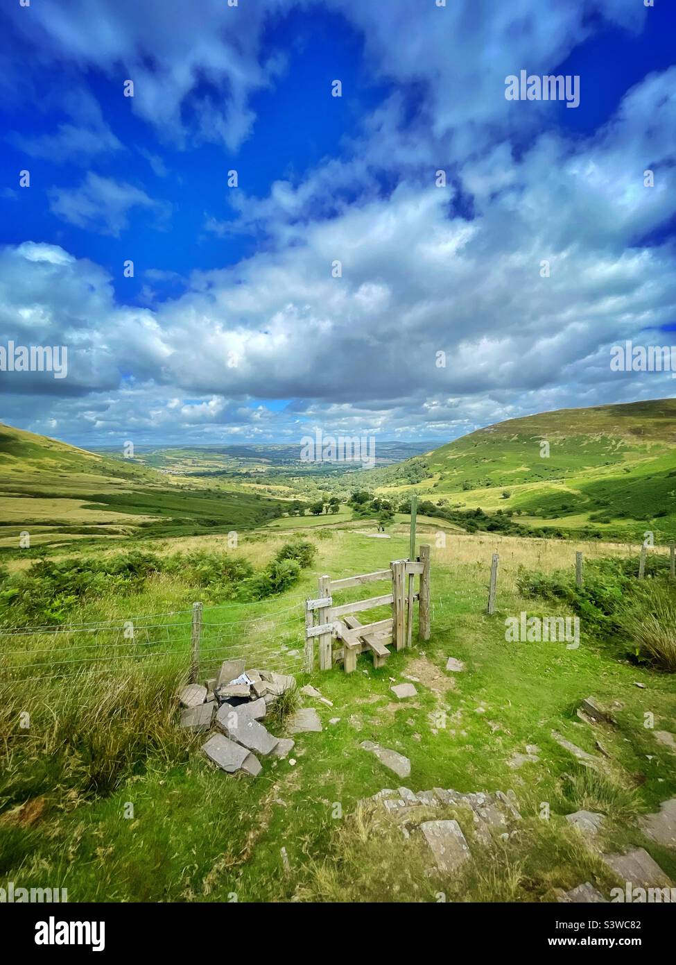 Stile in the Brecon Beacons, Cwm Llwch valley, with two walkers in far distance. Stock Photo