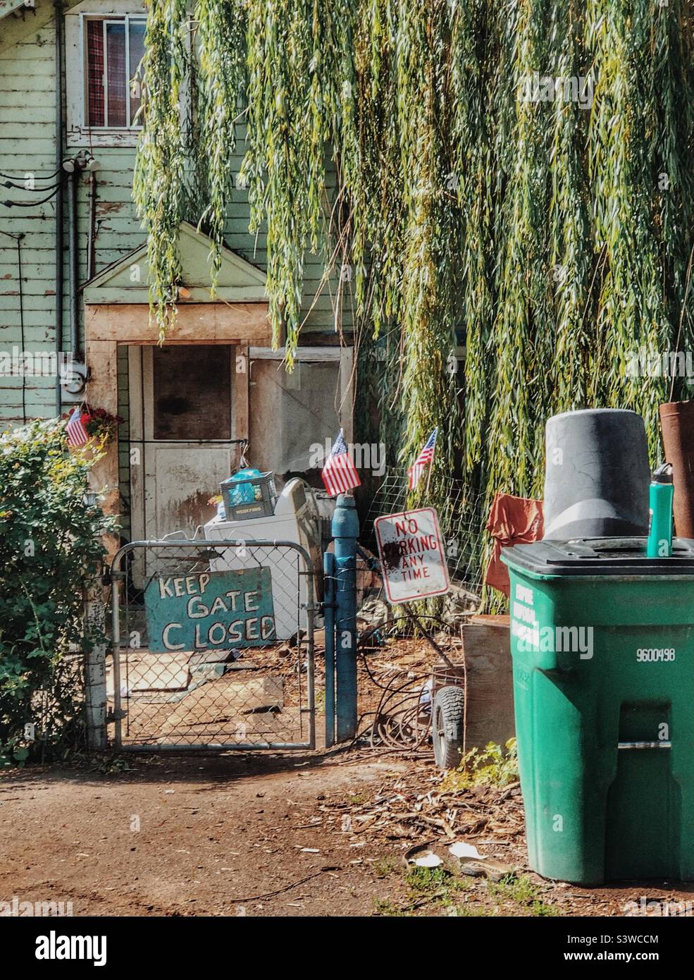 House with littered yard and hand painted sign on the gate - Smartphone Captured Stock Image