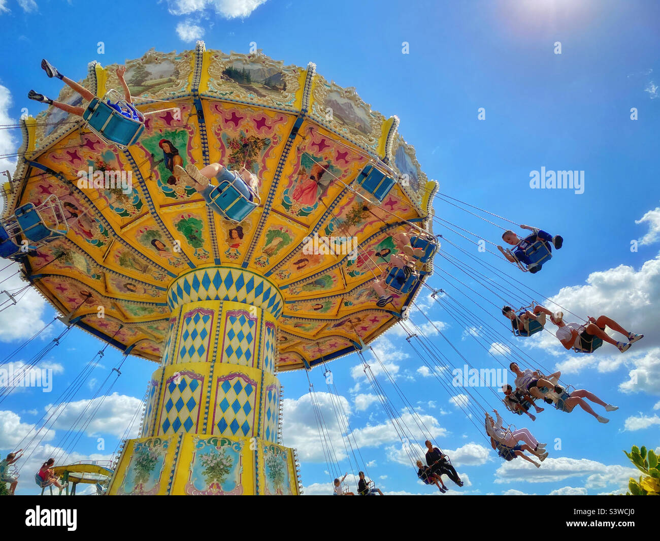 People enjoy riding on the sky swinger carousel ride at a summer fun fair. You can’t beat family summer fun at the Fayre! Photo ©️ COLIN HOSKINS. Stock Photo