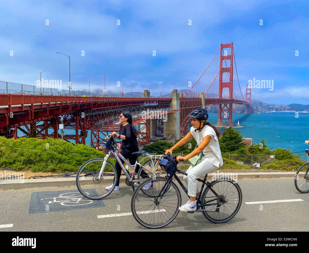 Cyclists on hire bikes ride past The Golden Gate Bridge in San Francisco, California. - Smartphone Captured Stock Image