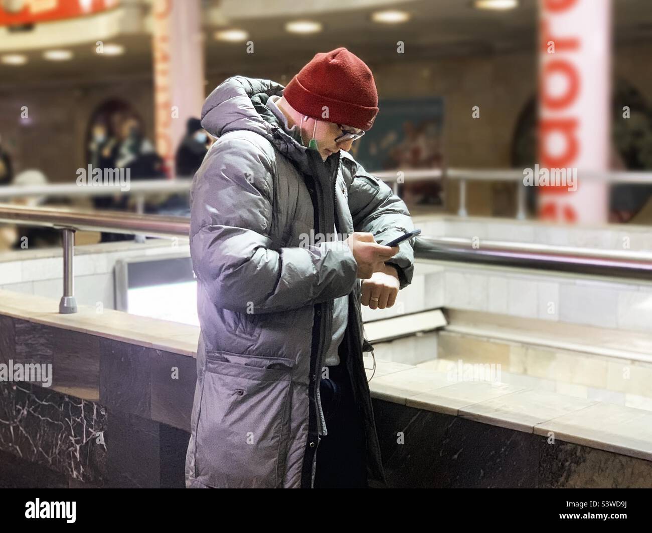 Young man using mobile phone in winter clothes - Smartphone Captured Stock Image