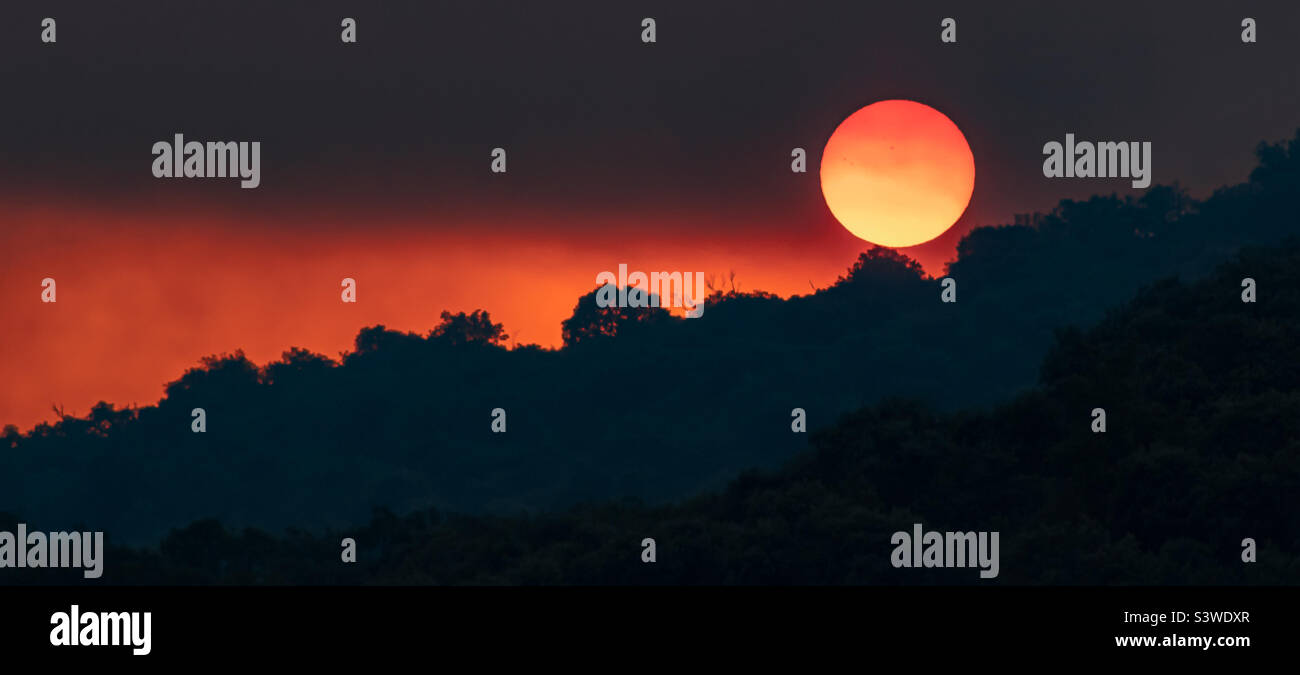 Sunset partially obscured by dark clouds of smoke from wildfires in