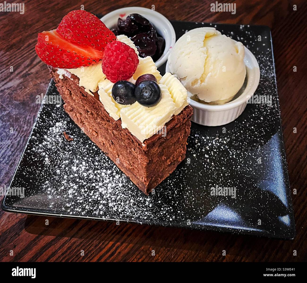 ‘Indulgence’ Chocolate layer cake with cherry compote and vanilla ice cream Stock Photo Alamy