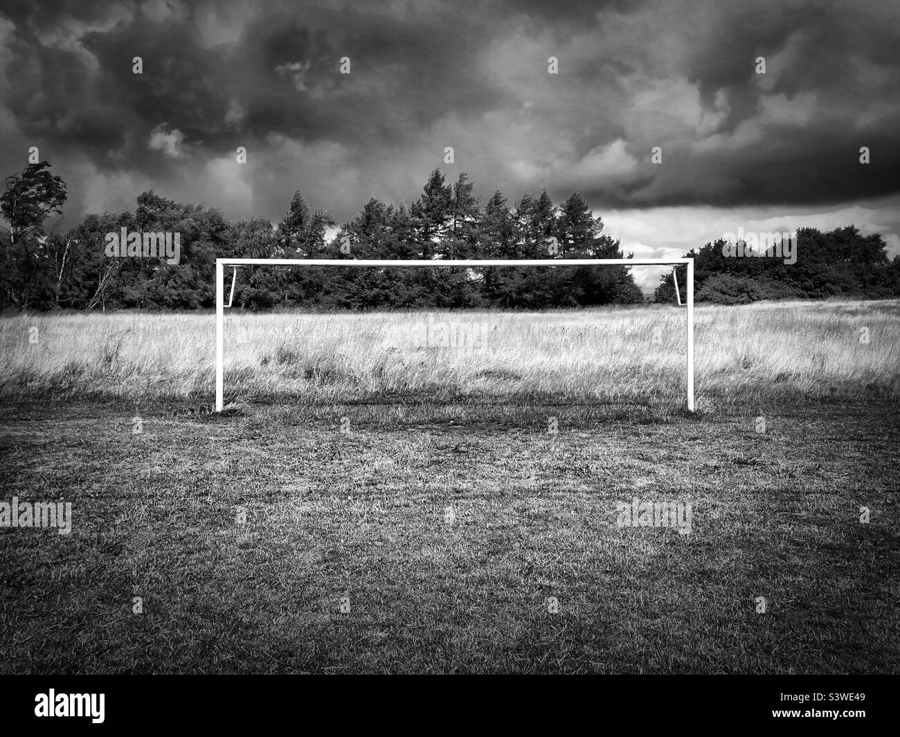 ‘Open Goal’ lonely goalposts ready for the season to return as the cloud above means any practice may also be on hold… for now (Black & White) Stock Photo