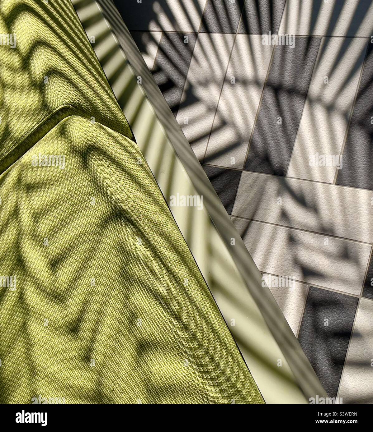 Upholstery cushions and floor tiles shadowed by a decorative screen on board a cruise liner. - Smartphone Captured Stock Image