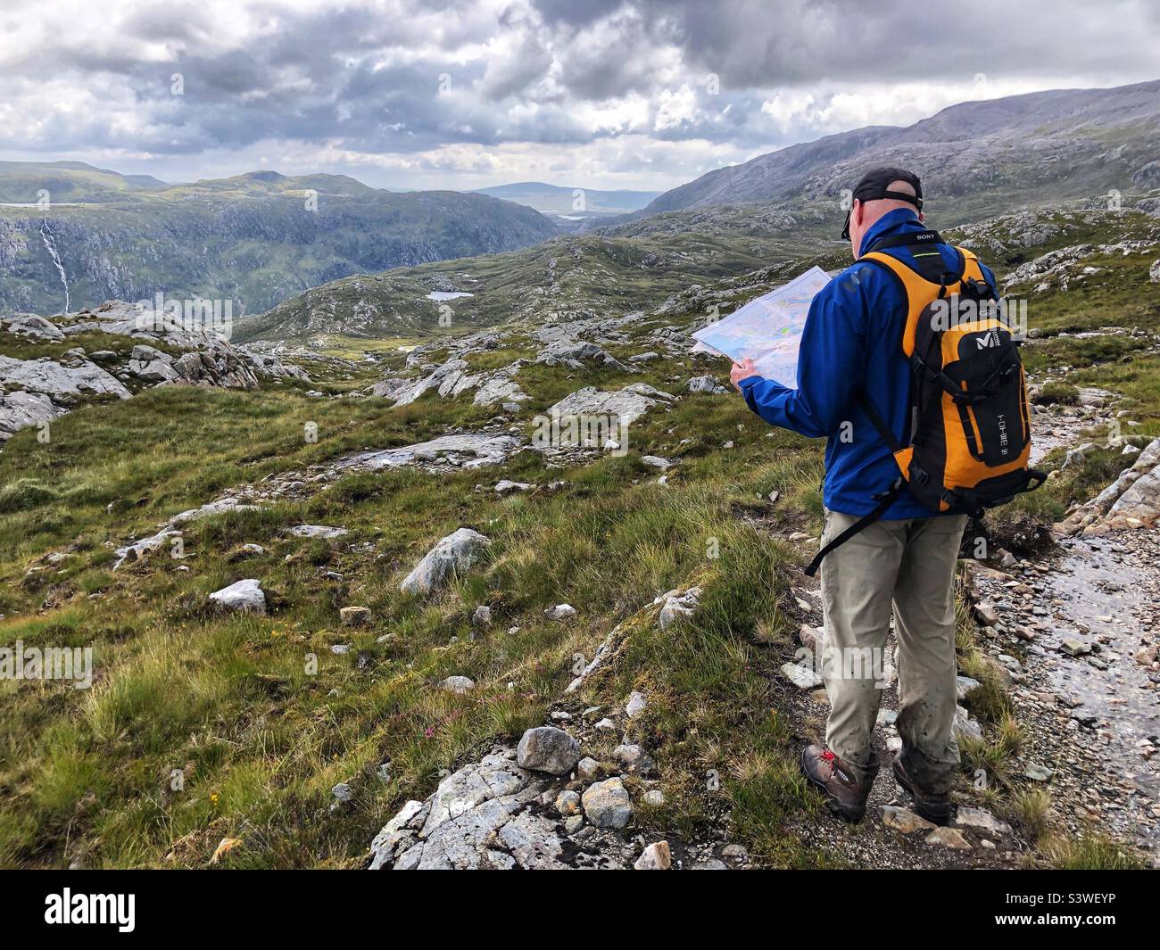 Mature man Lost and reading a map in the Scottish Highlands, Inverpolly estate, north west Scotland - Smartphone Captured Stock Image