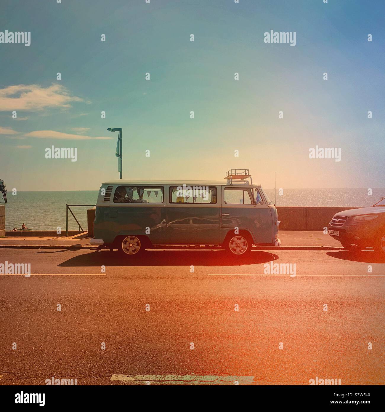 A vintage retro VW camper van parked at the seaside in the summer - summertime holiday road trip Stock Photo