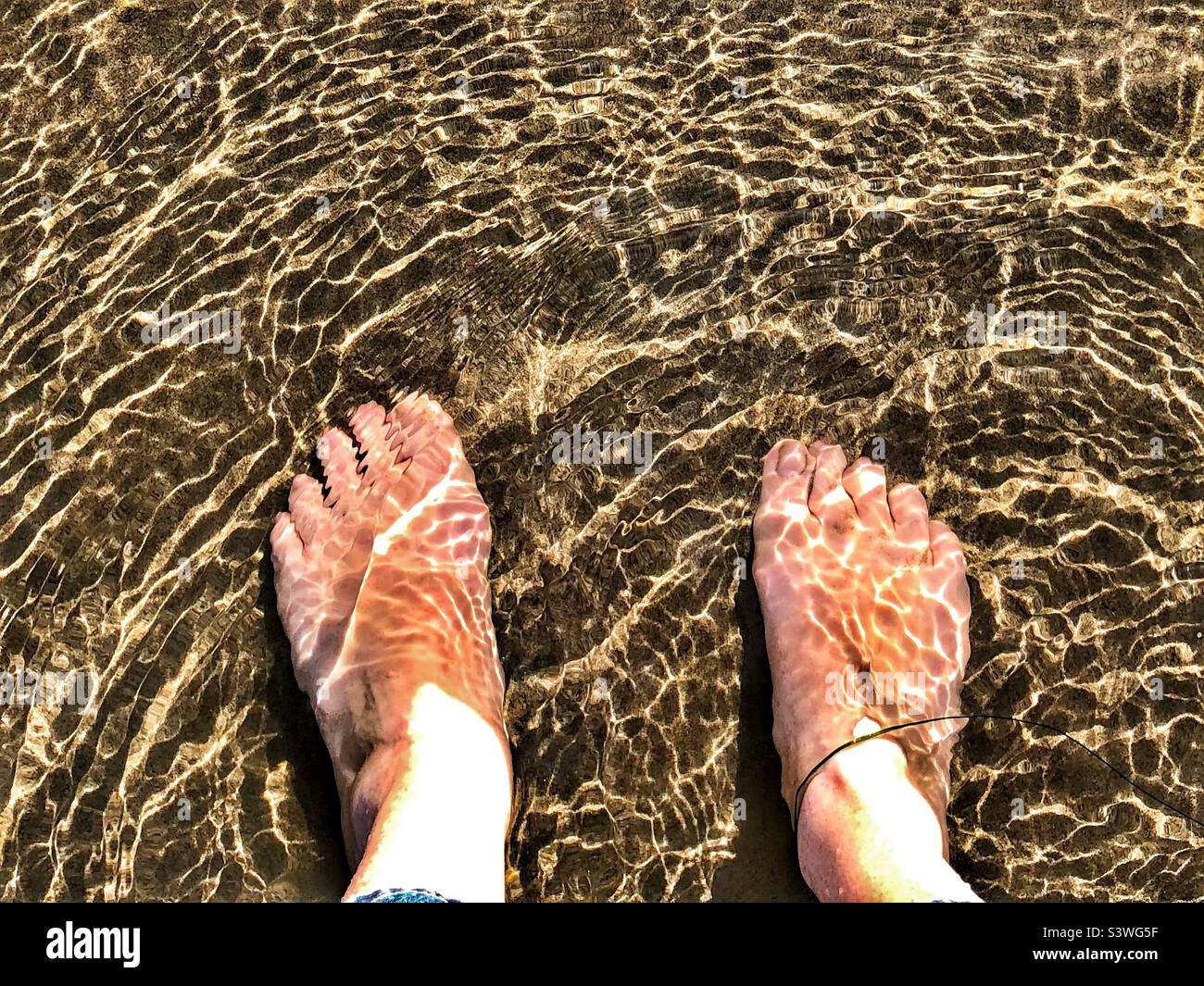 My feet momentarily dipped in the icy water at Cannon Beach, Oregon, in July Stock Photo