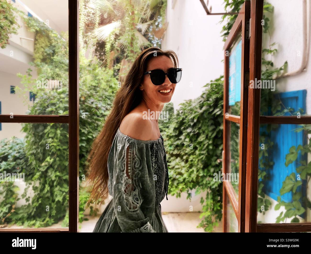 Young happy woman standing at the opened window - Smartphone Captured Stock Image