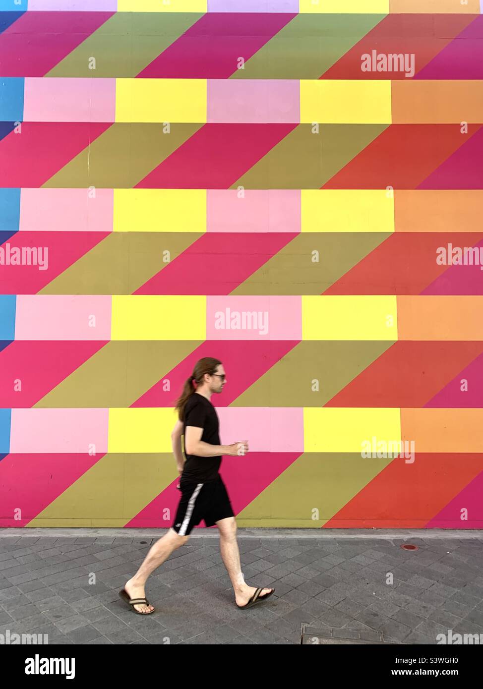 Man walking against colourful wall in North Greenwich - Smartphone Captured Stock Image