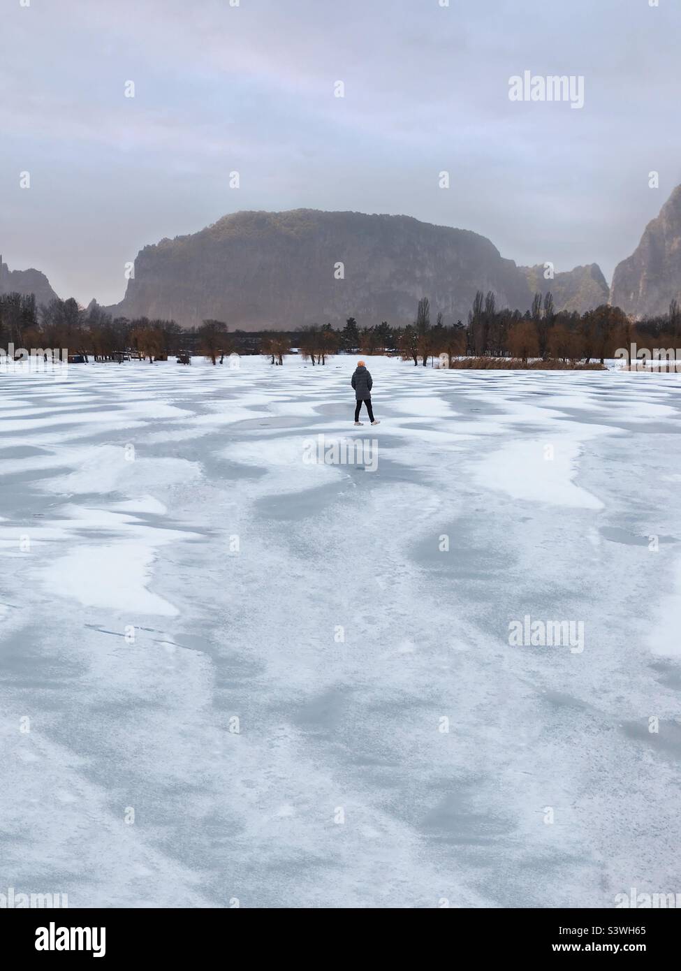 Tiny human walking by the frozen lake in winter - Smartphone Captured Stock Image