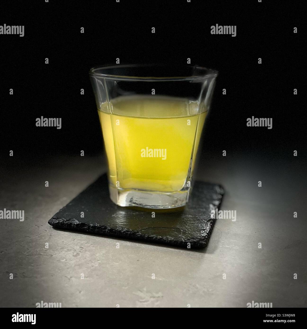 Glass of Orange Squash on a slate coaster Stock Photo