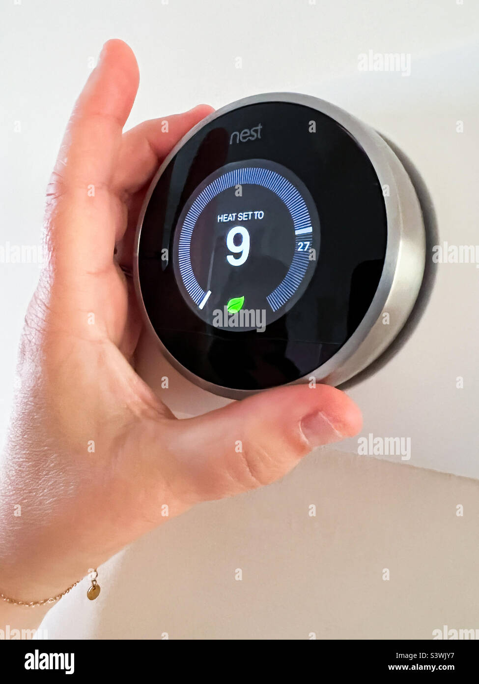 Homeowner turning down Google Nest smart thermostat on a very hot day in England UK Stock Photo