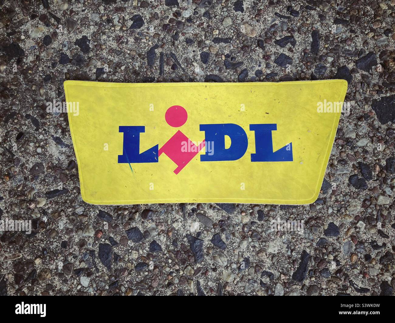 A Piece of Plastic with the Brandname Lidl on it laying on the Asphalt Stock Photo