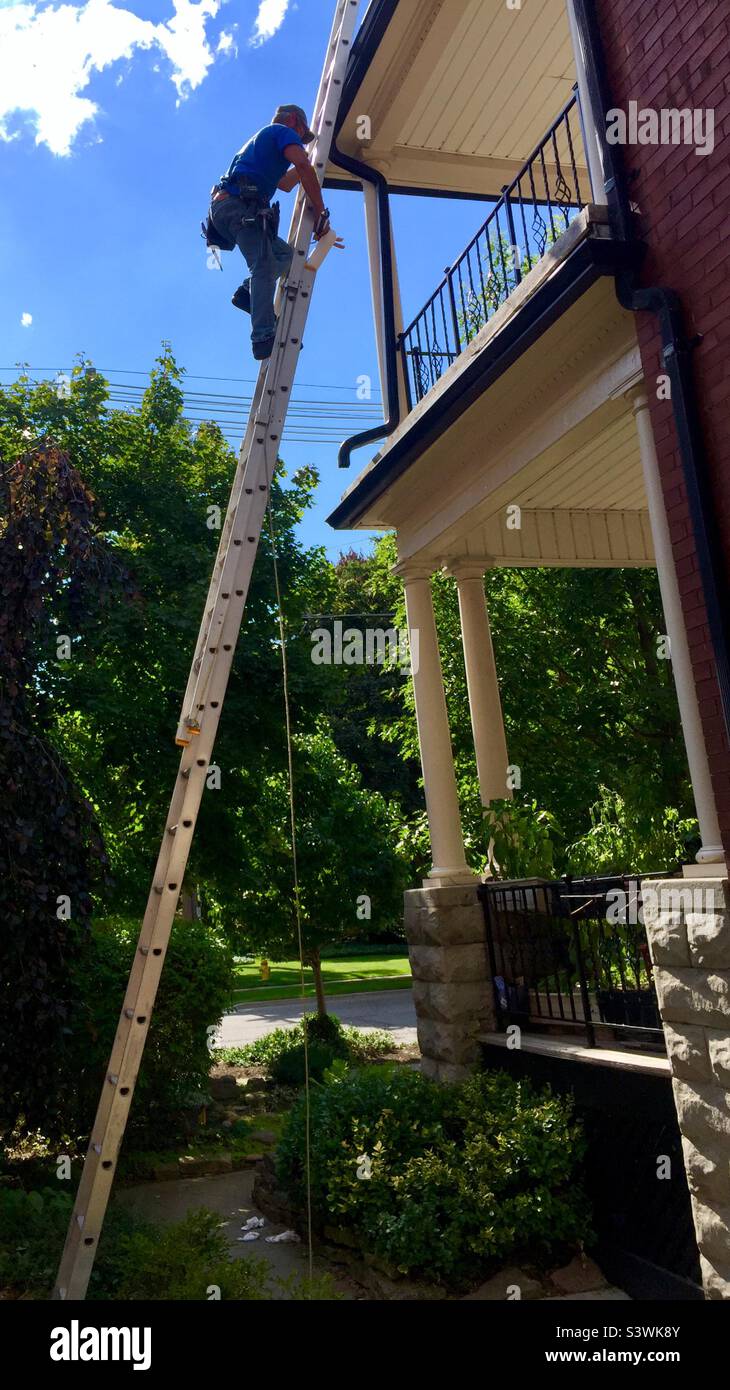 Worker on a tall ladder. Off the ground. Two storeys. Reaching for the