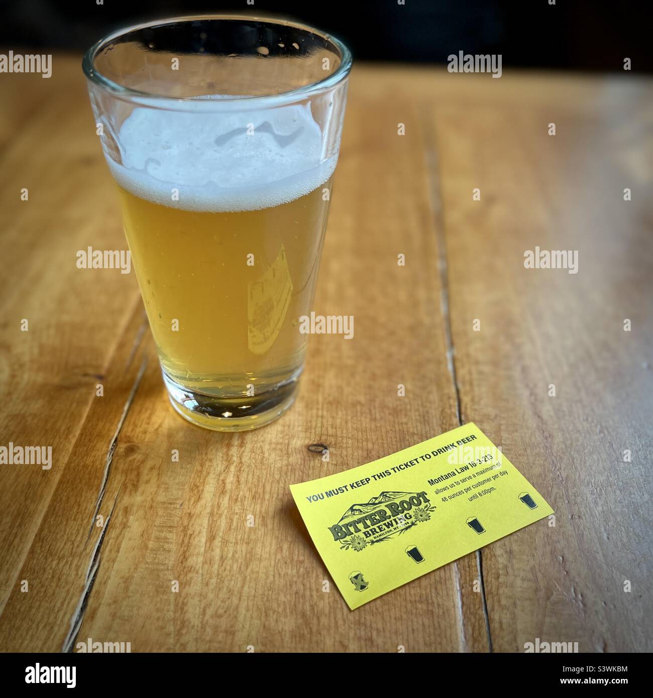 HAMILTON, MT, MAY 2022: pint of beer with yellow ticket showing number of alcoholic drinks consumed for local law compliance at Bitter Root Brewing - Smartphone Captured Stock Image