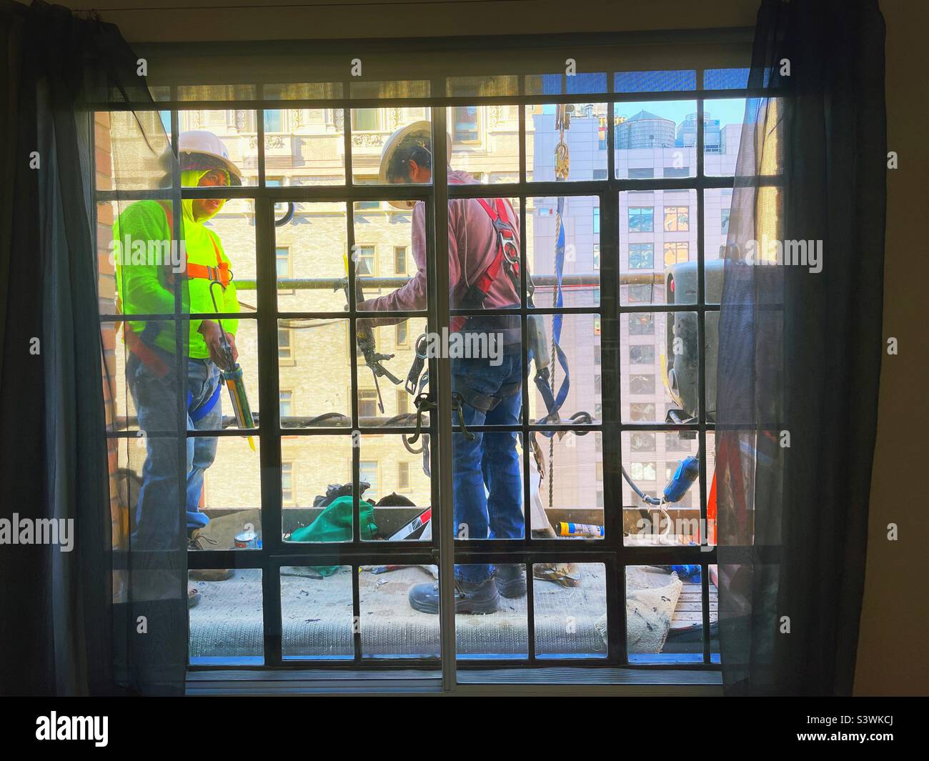 Workers on a suspended platform outside a high-rise casement window in Murray Hill, 2022, New York City, USA Stock Photo