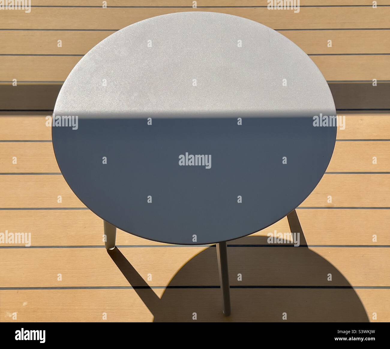 A small circular table in light and shadow on the balcony of a cruise liner. - Smartphone Captured Stock Image