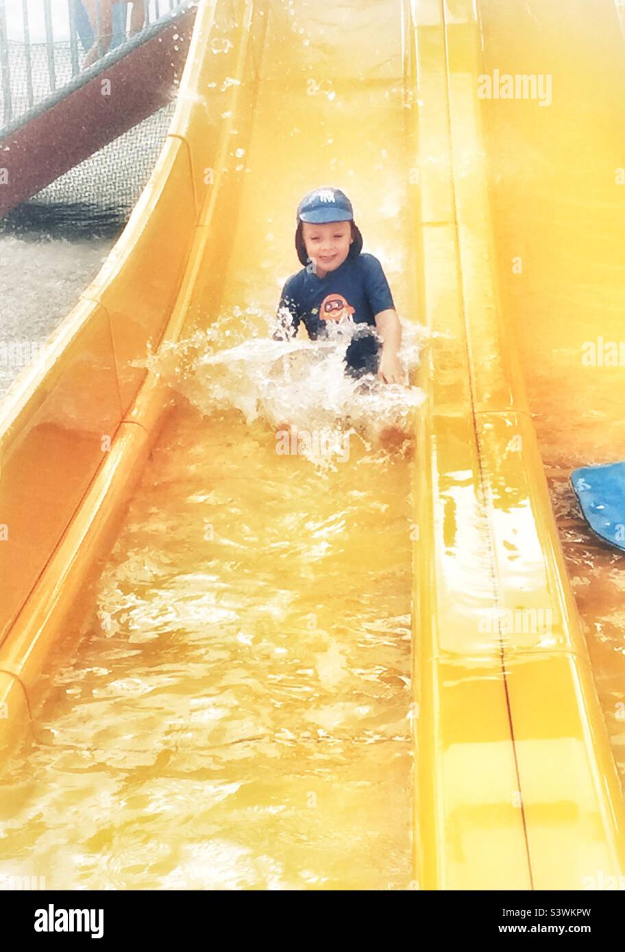 Child on a yellow water slide Stock Photo