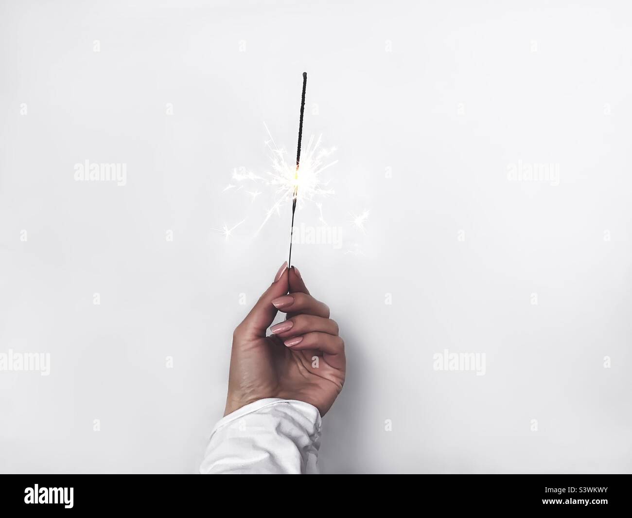 Female hand holding festive sparkles on white background - Smartphone Captured Stock Image