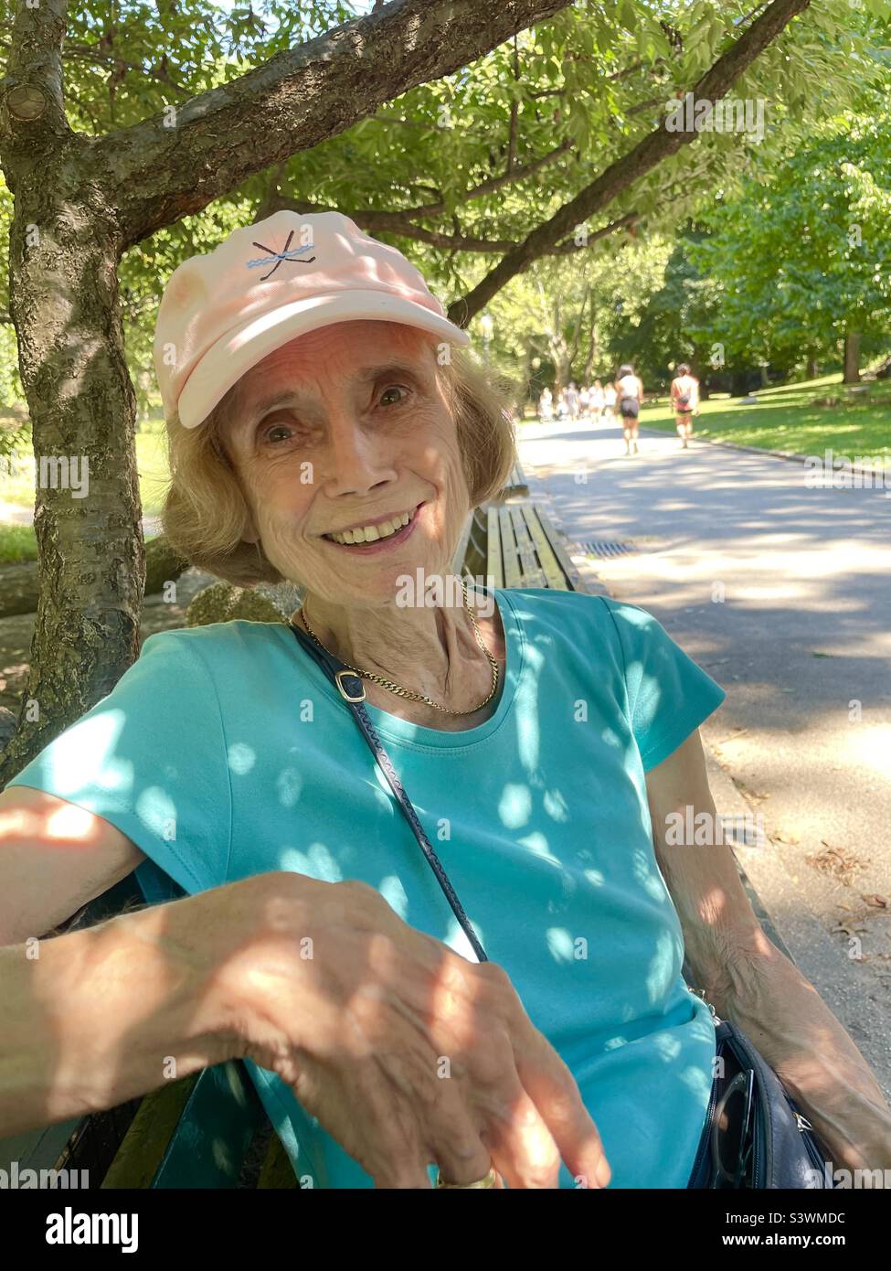 Dappled sunlight on a woman sitting in Central Park, New York City, NYCC, USA - Smartphone Captured Stock Image