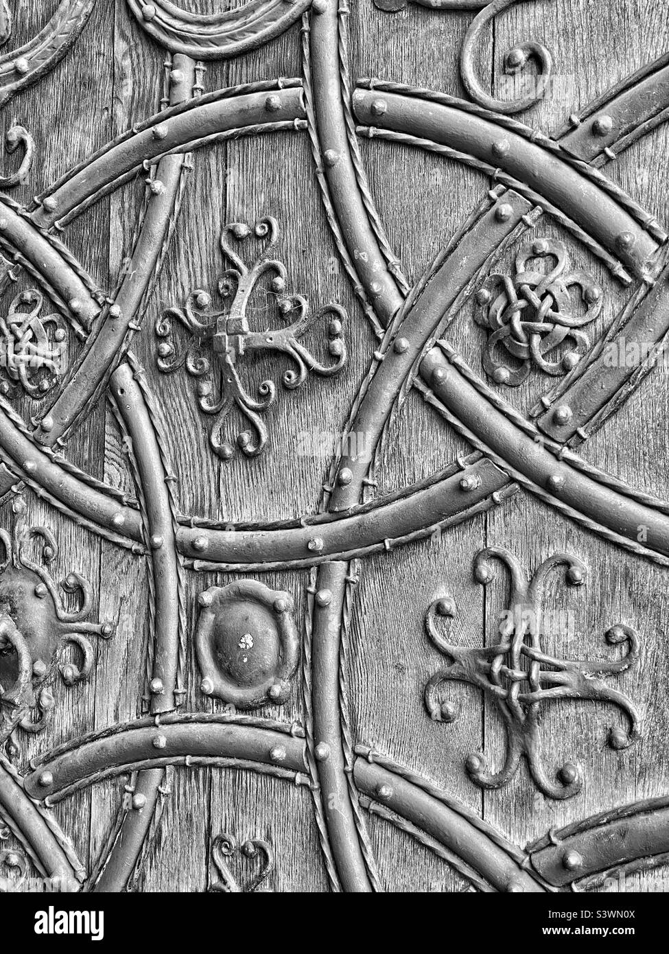 A monochrome image showing the exquisite ironwork design and detail on the Great West Door of Rochester Cathedral in Kent, England. This cathedral is a Grade 1 listed building. Photo ©️ COLIN HOSKINS. Stock Photo