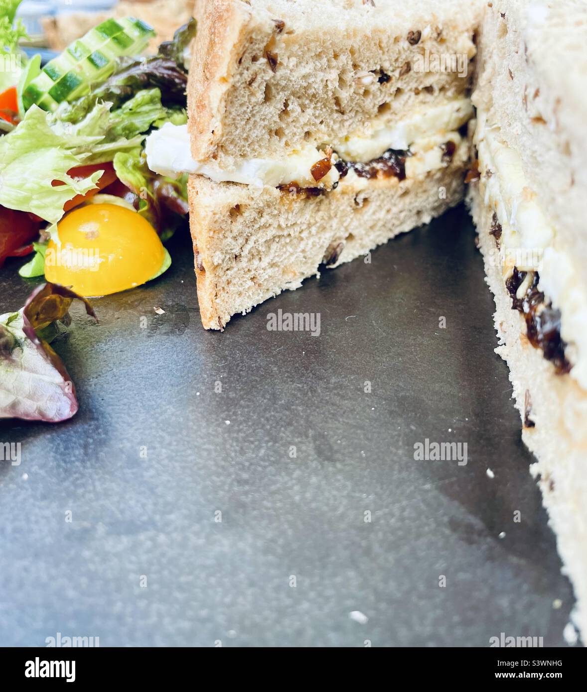 Doorstop Sandwich! Thick slices of granary bread with Brie and red onion chutney, side salad. Stock Photo