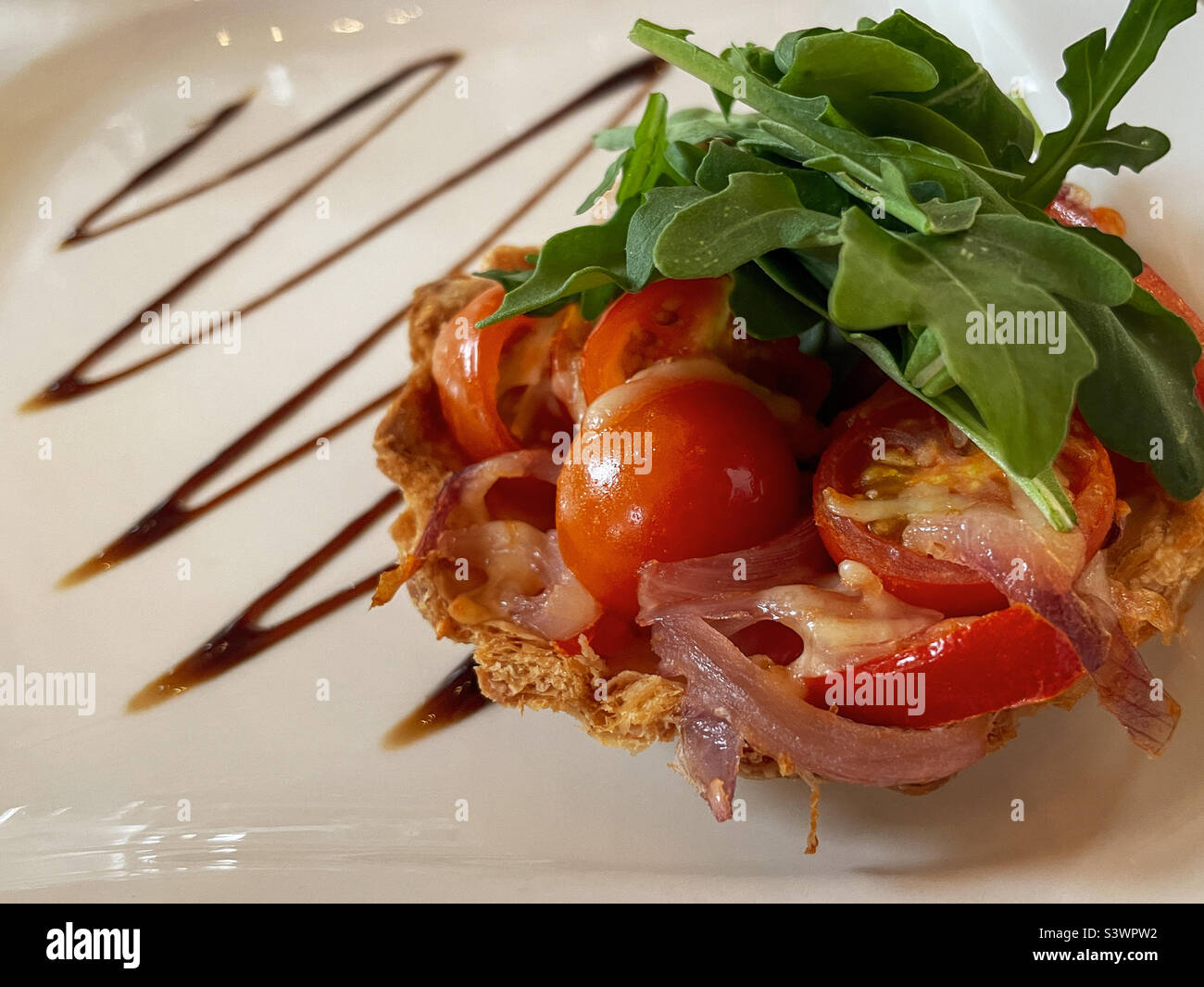 Tomato and bacon tartlet with rocket lettuce Stock Photo