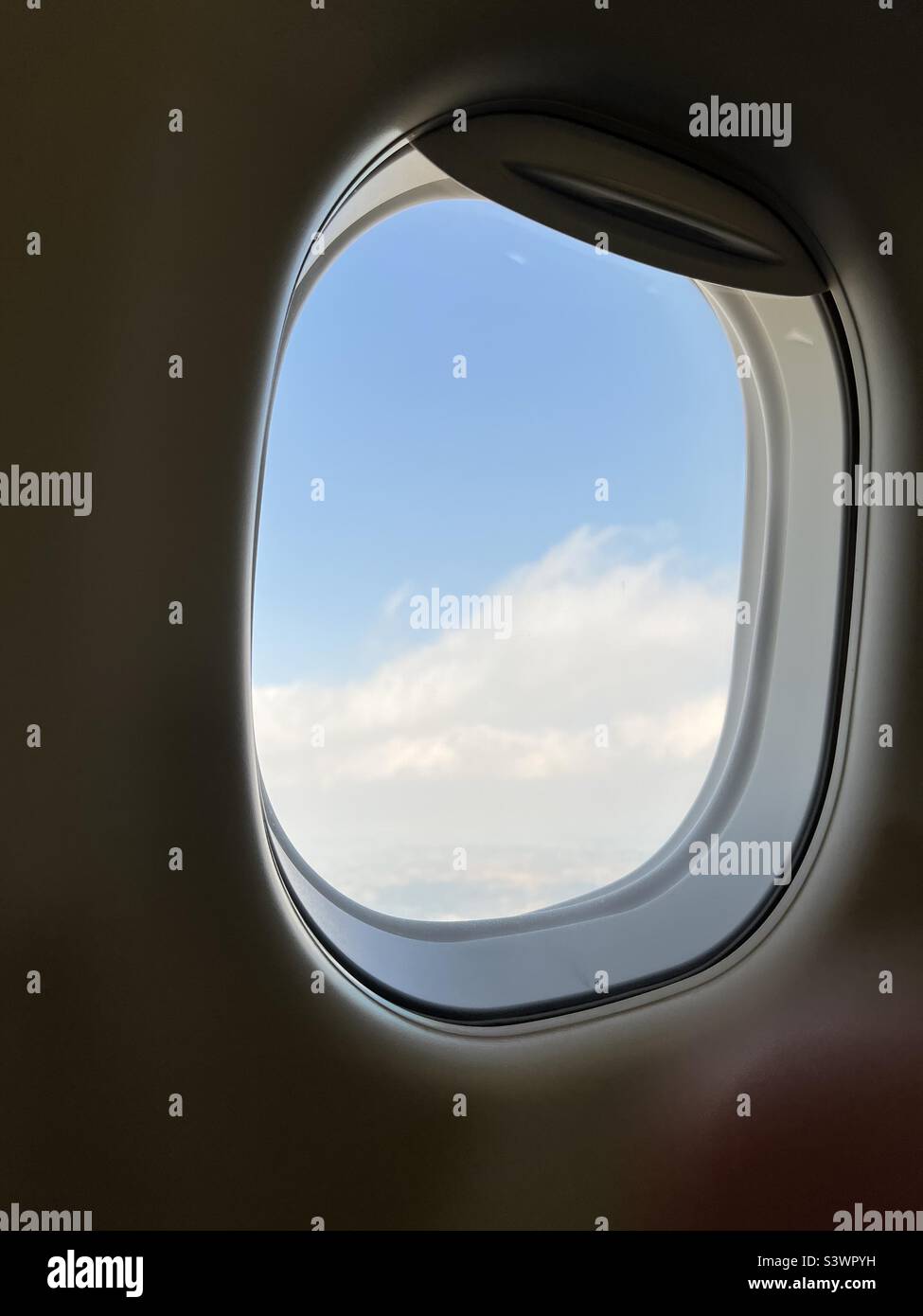 View of clouds and blue sky through passenger aircraft window - Smartphone Captured Stock Image