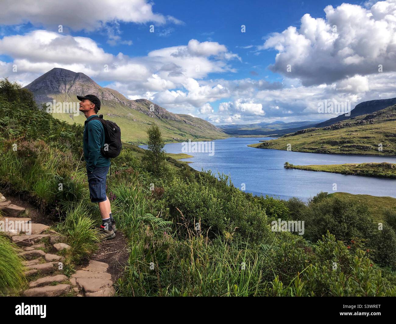 Walker on the path approach to Stac Pollaidh or Stack Polly, mountain in Inverpolly, with a view of Loch Lurgainn, North West Scotland - Smartphone Captured Stock Image