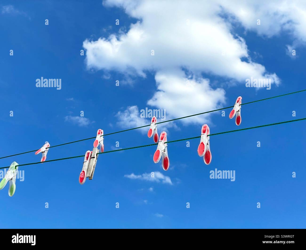 Colourful pegs on a washing line against a blue sky with clouds. - Smartphone Captured Stock Image