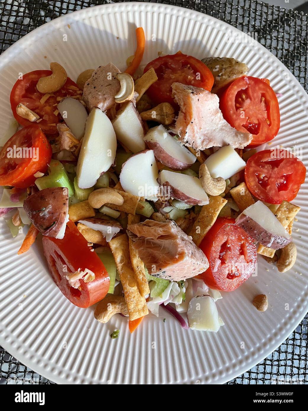 A healthy maincourse salad of broiled salmon chunks and new potatoes over a bed of lettuce with heirloom tomatoes, 2022, USA Stock Photo