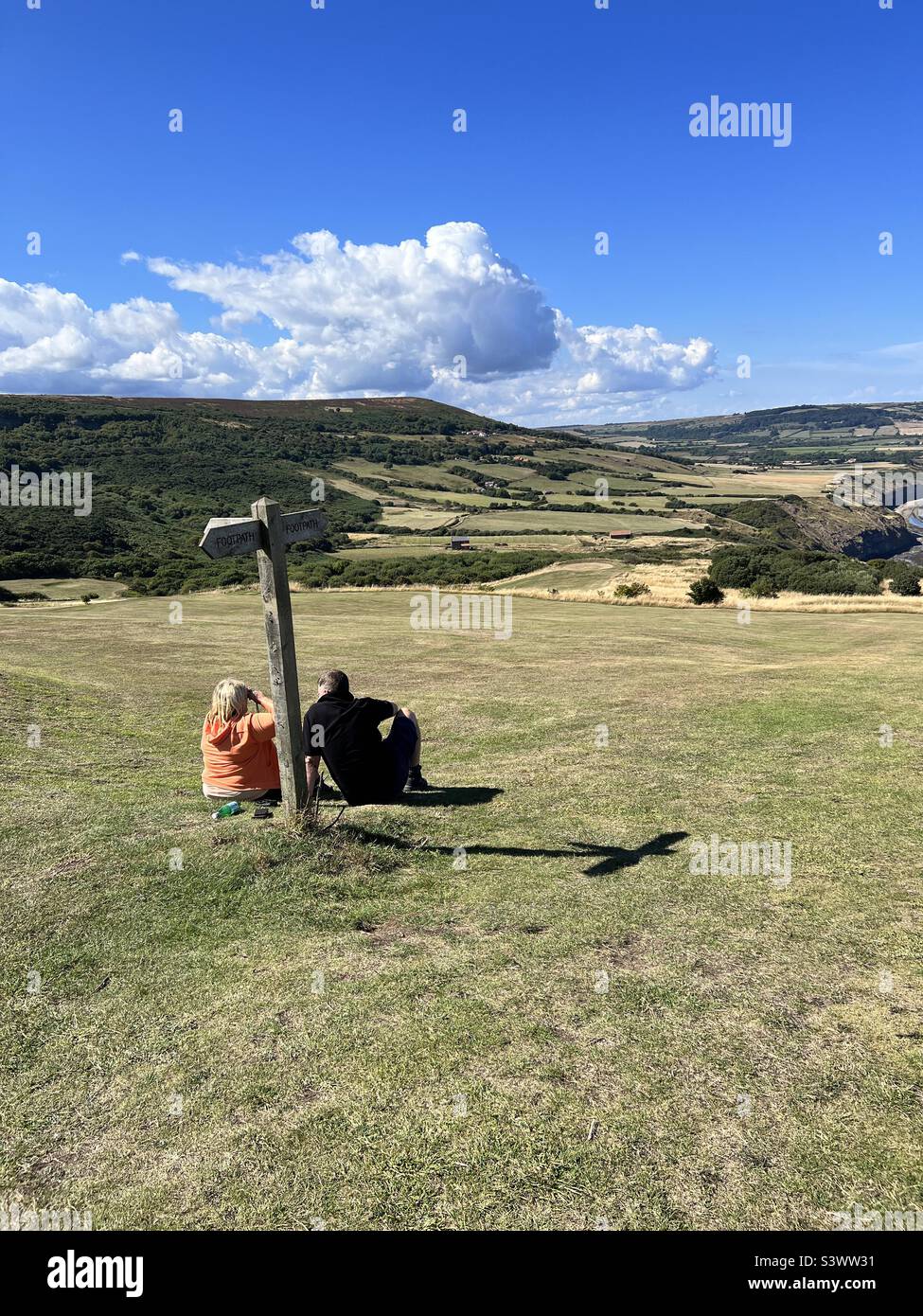 Couple resting by a signpost and taking in the view Stock Photo