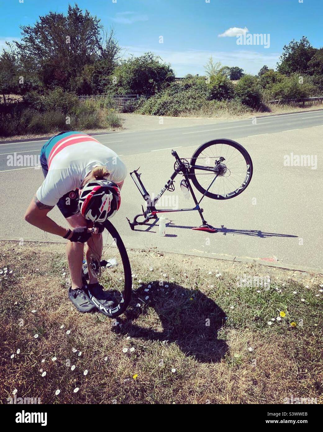 A man fixes a bicycle puncture beside the road - Smartphone Captured Stock Image