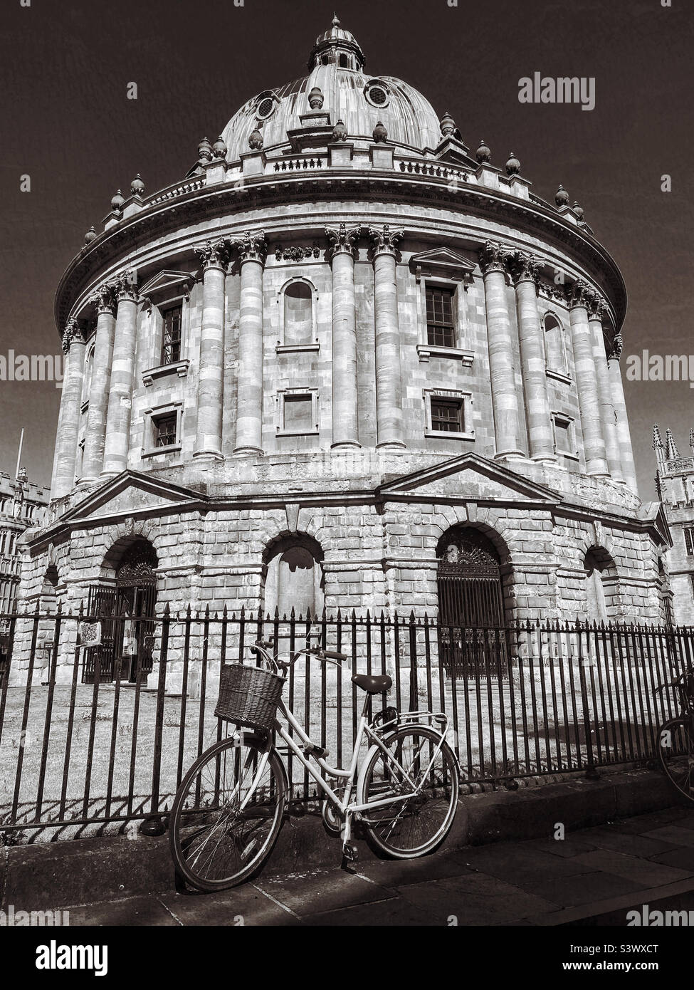A bicycle is chained to the railings outside the Radcliffe Camera Building in Radcliffe Square, Oxford, England. This Palladian- style building is used as a library by students. Photo ©️ COLIN HOSKINS Stock Photo