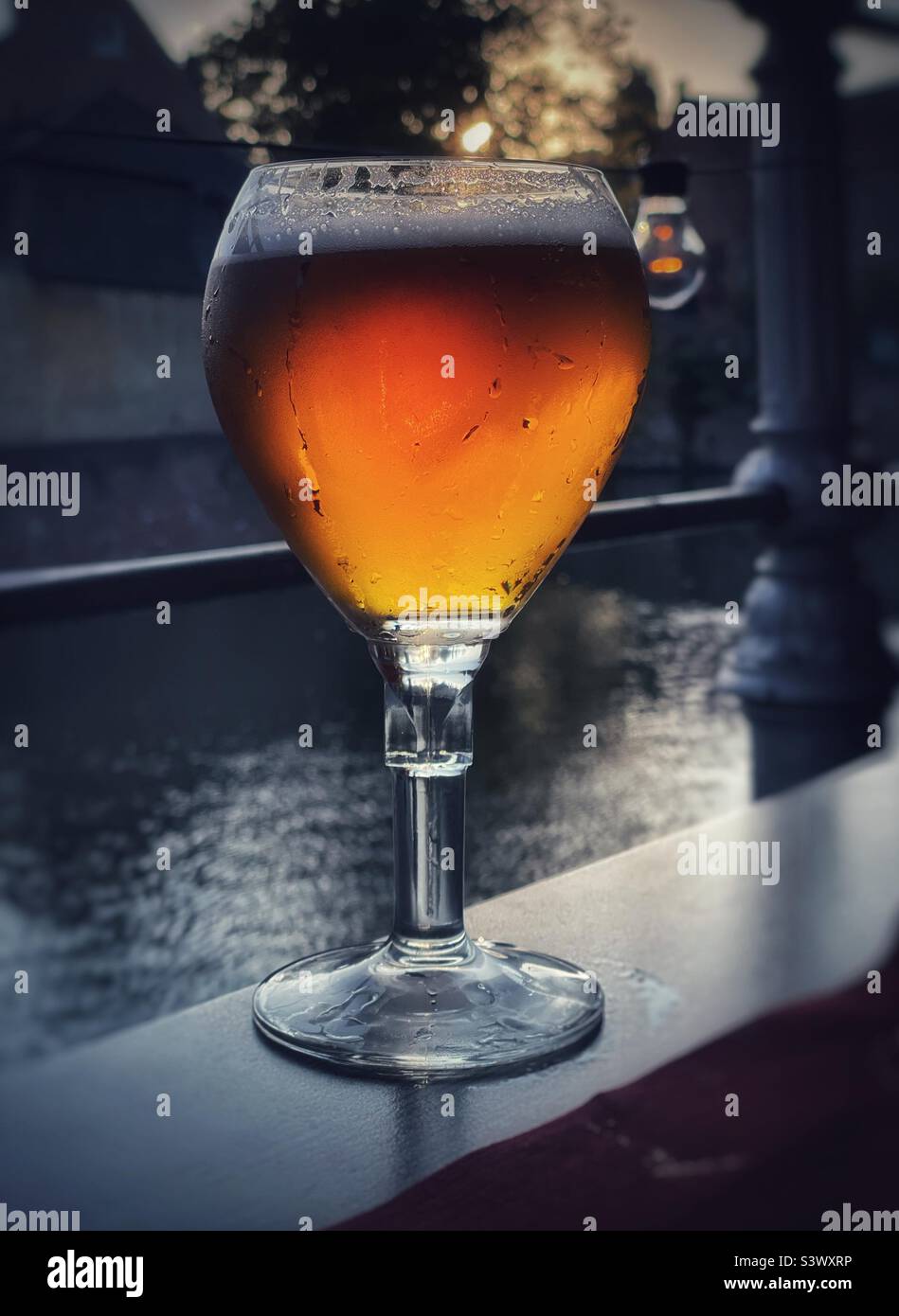 A glass of cold Belgian beer on a waterside restaurant table in Bruges, Belgium, August. Stock Photo