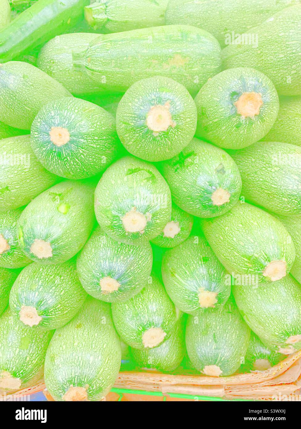 Bright faded view of fresh zucchini stacked in the market. Stock Photo