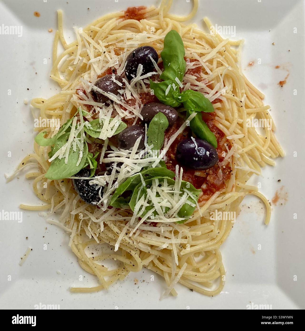 Homemade spaghetti sauce with gluten free pasta, topped with Kalamata olives, fresh garden picked basil, parmigiano reggiano and fresh cracked pepper. Stock Photo